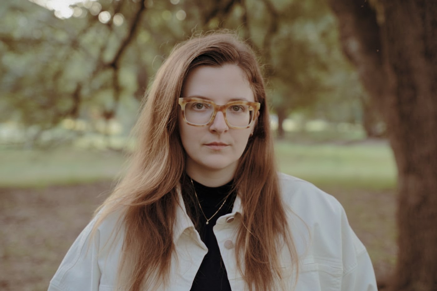 Portrait of A.E. Haskett standing outdoors under trees.